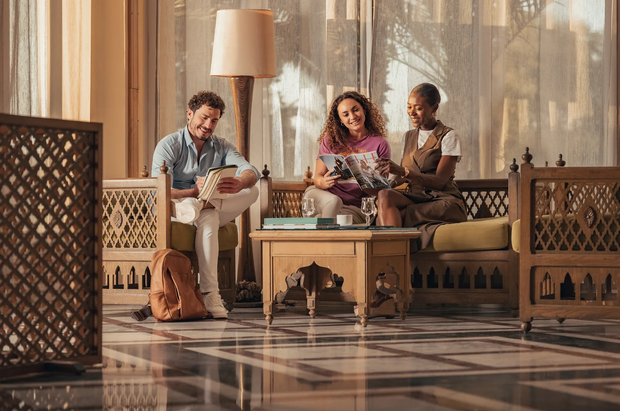 Three friends looking through magazines in a hotel lounge in Tunisia, Verdi Hotels, part of Corinthia Group