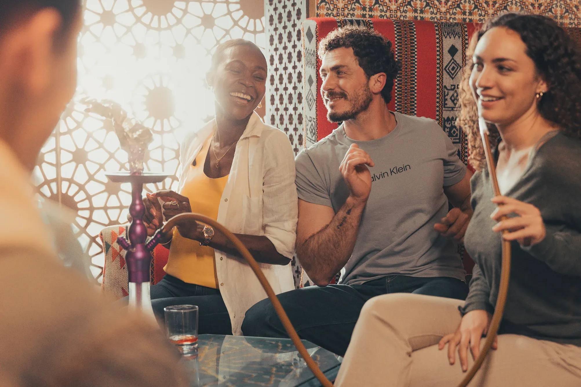 Friends laughing together around a shisha pipe in a lounge in Tunisia