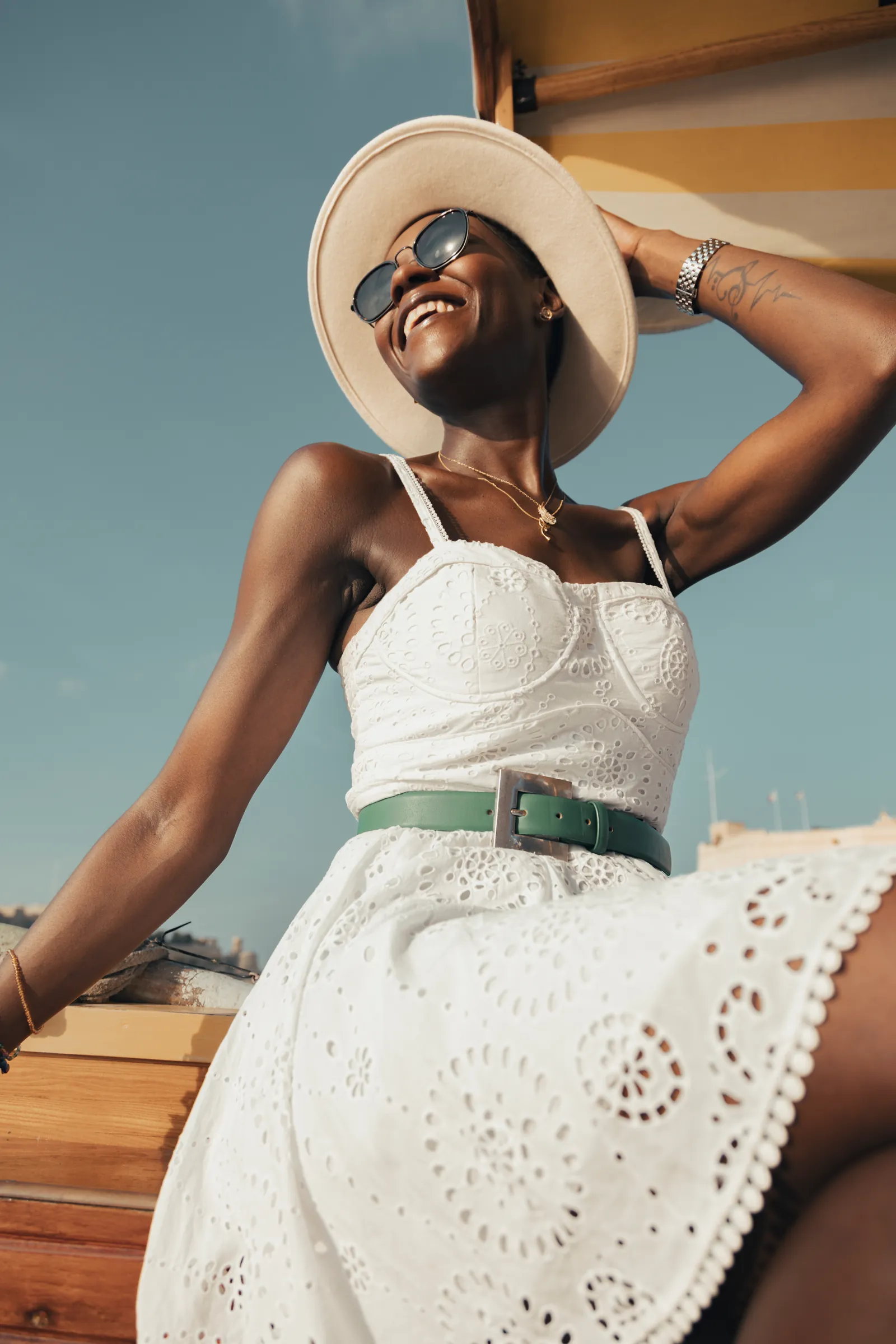 Woman in a white sundress and sunhat laughing in the sunshine