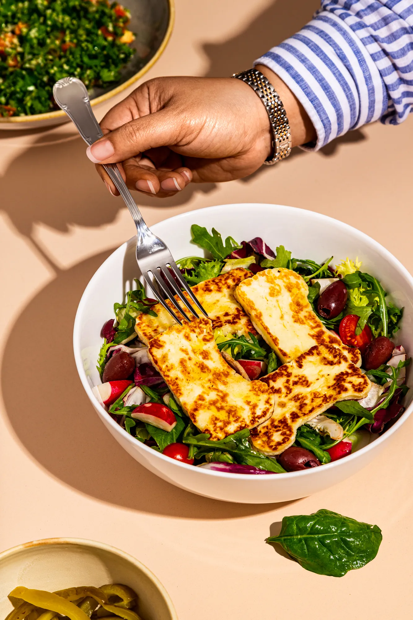 Hand with a fork over a halloumi salad, for Baba Lebanese Street Food