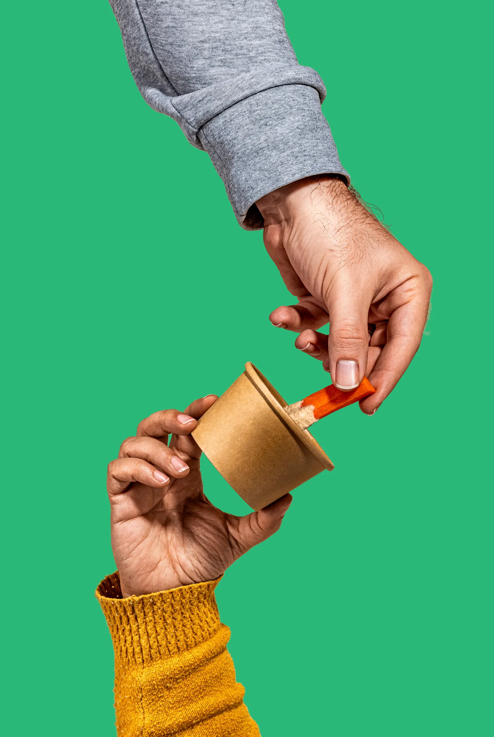 Hand holding a small gold dip pot against a green background