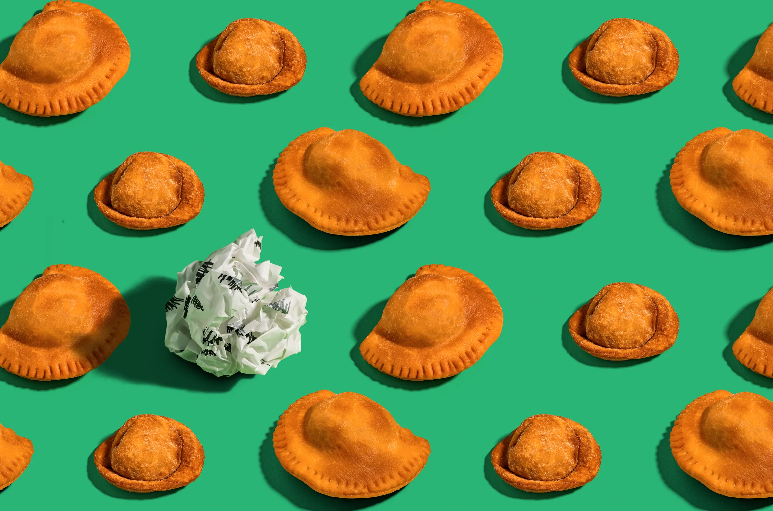 Sambousek pastries in rows on green with a crumpled paper wrap, for Baba Lebanese Street Food
