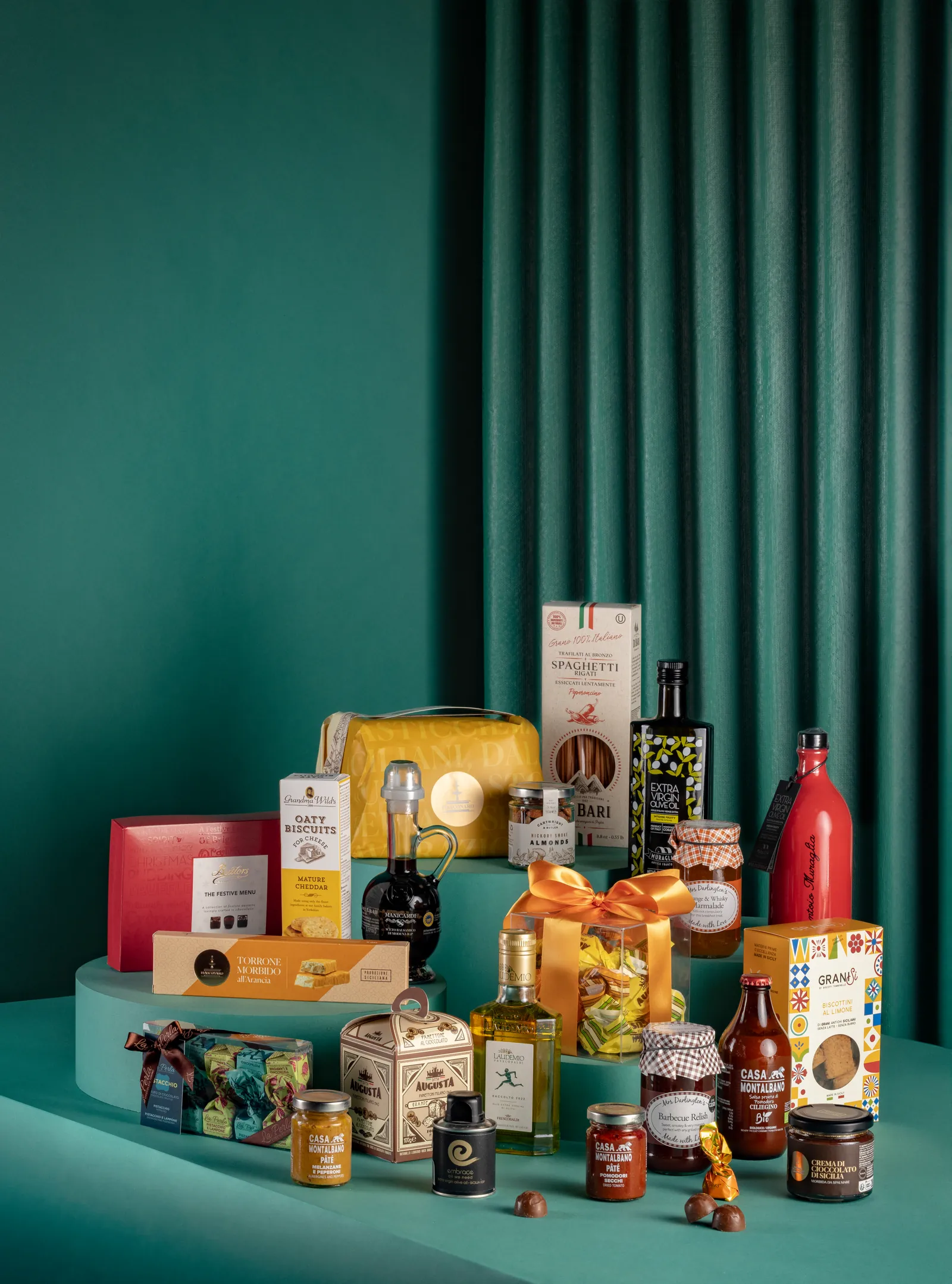 Christmas hamper on stepped teal platforms in front of a green pleated backdrop