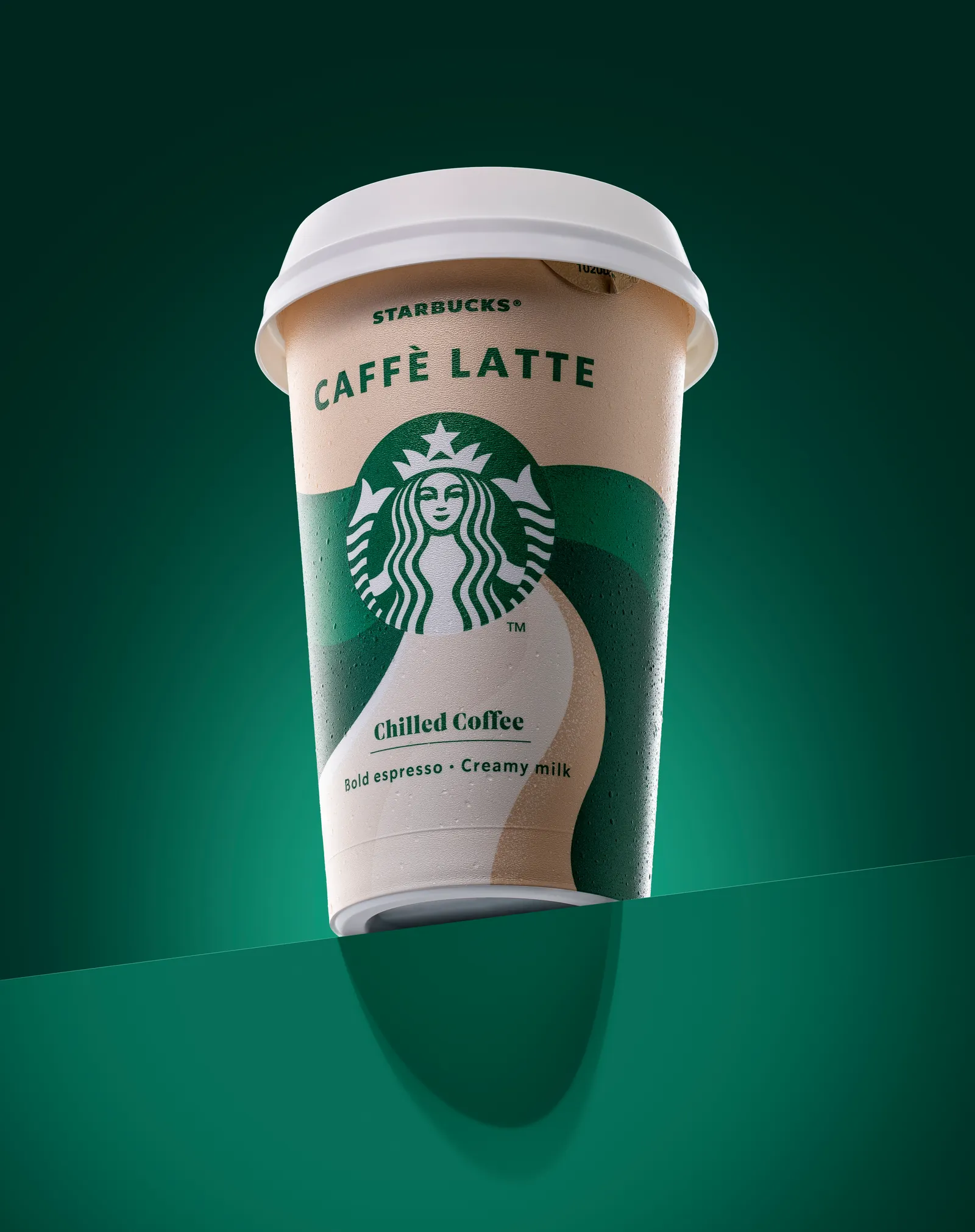 Chilled Starbucks caffè latte cup against a teal green background