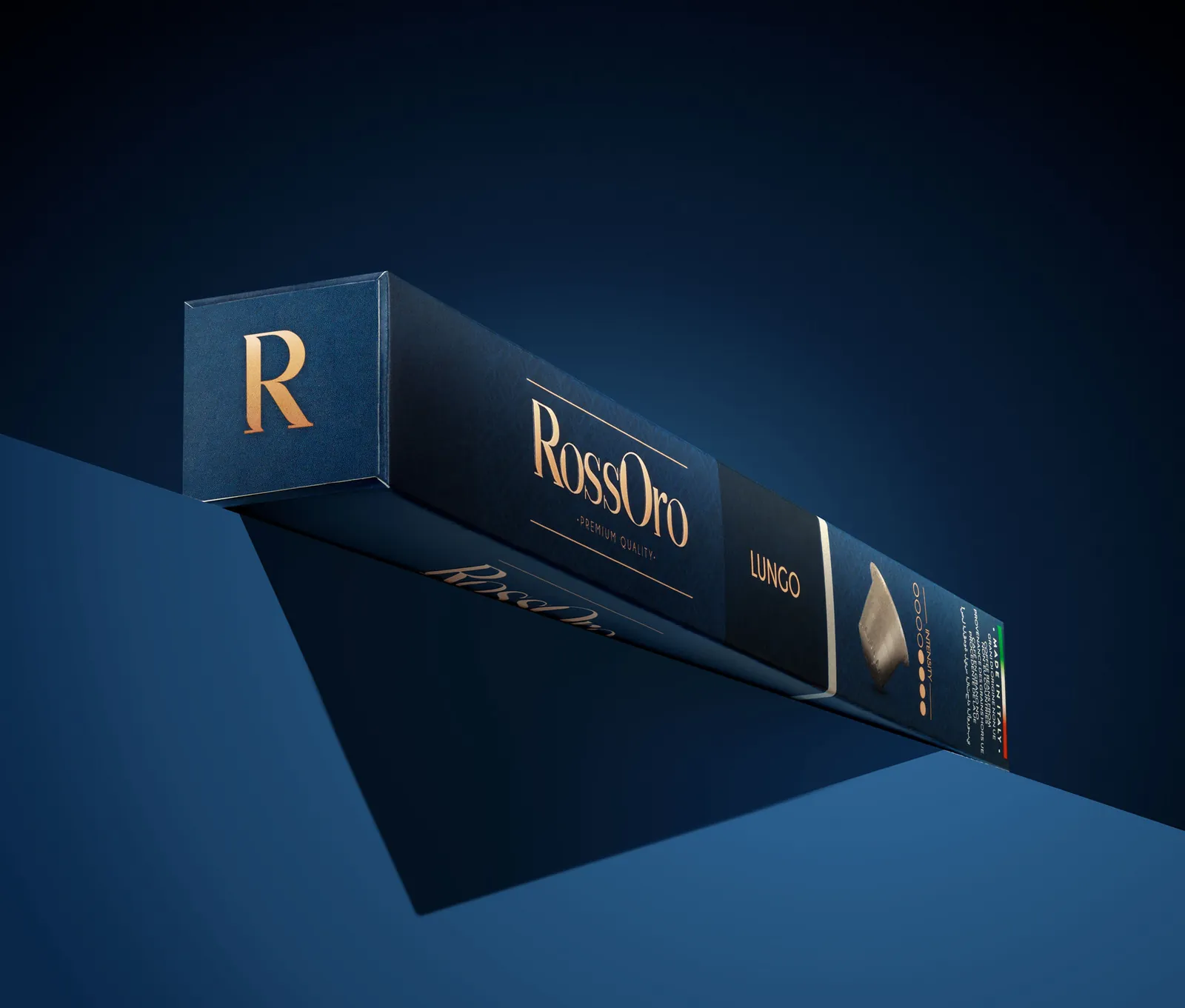 RossOro capsule box tilted on a deep blue backdrop with the gold R logo