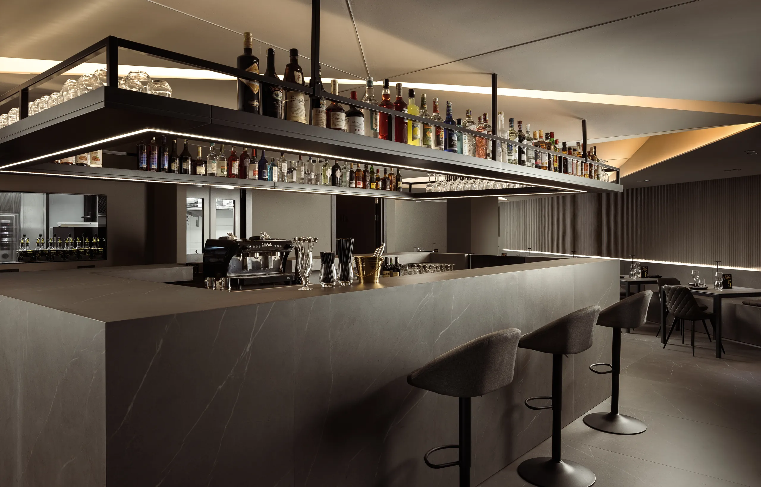 Hotel bar with a suspended bottle shelf and stools