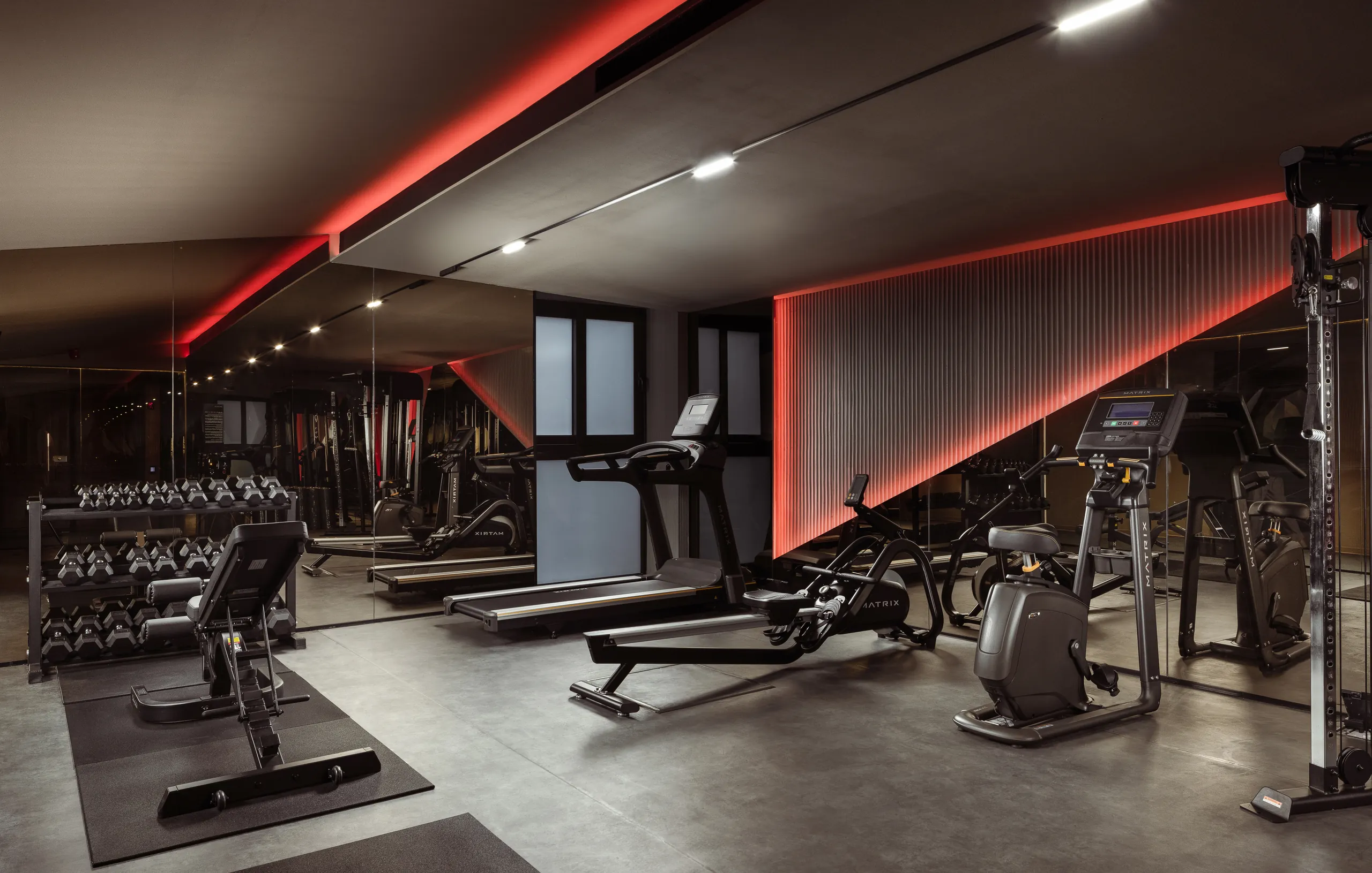 Hotel gym with a treadmill, weights and red strip lighting