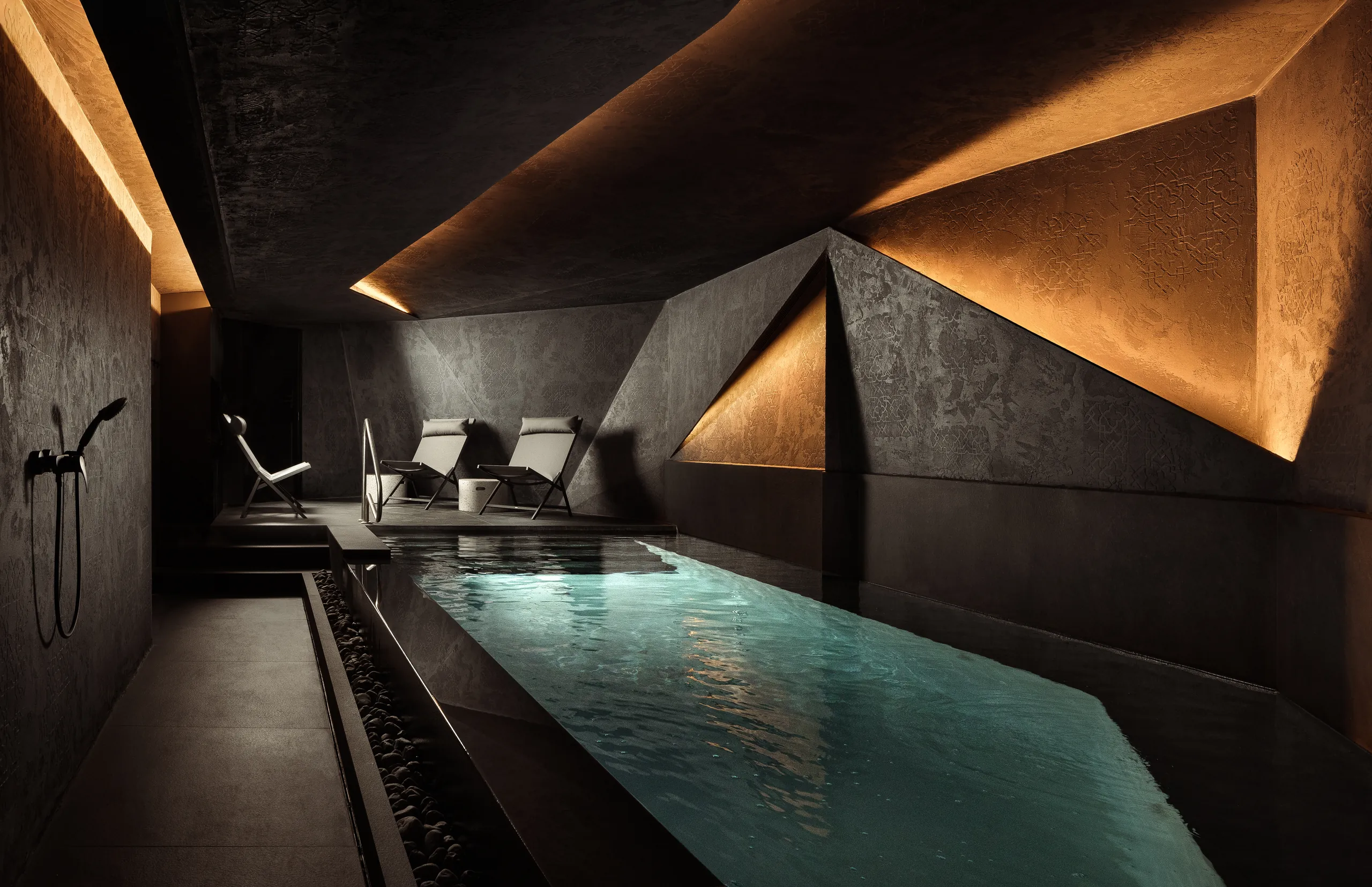Dark spa relaxation room with a narrow pool and angular lit walls