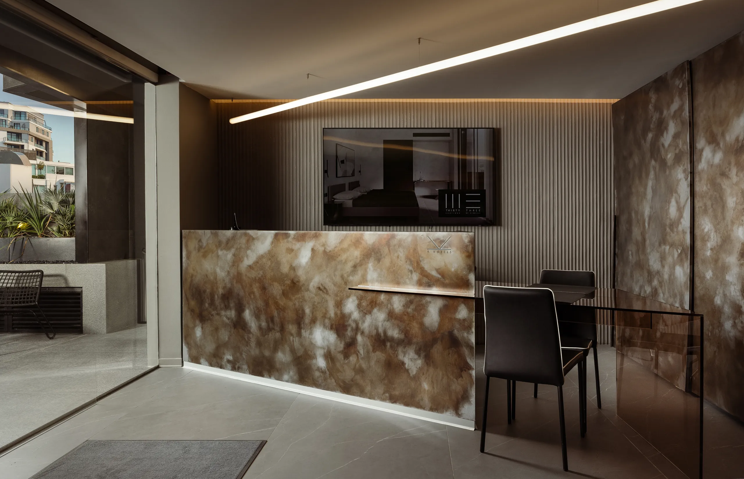Hotel reception desk with a patterned stone front and a wall-mounted TV
