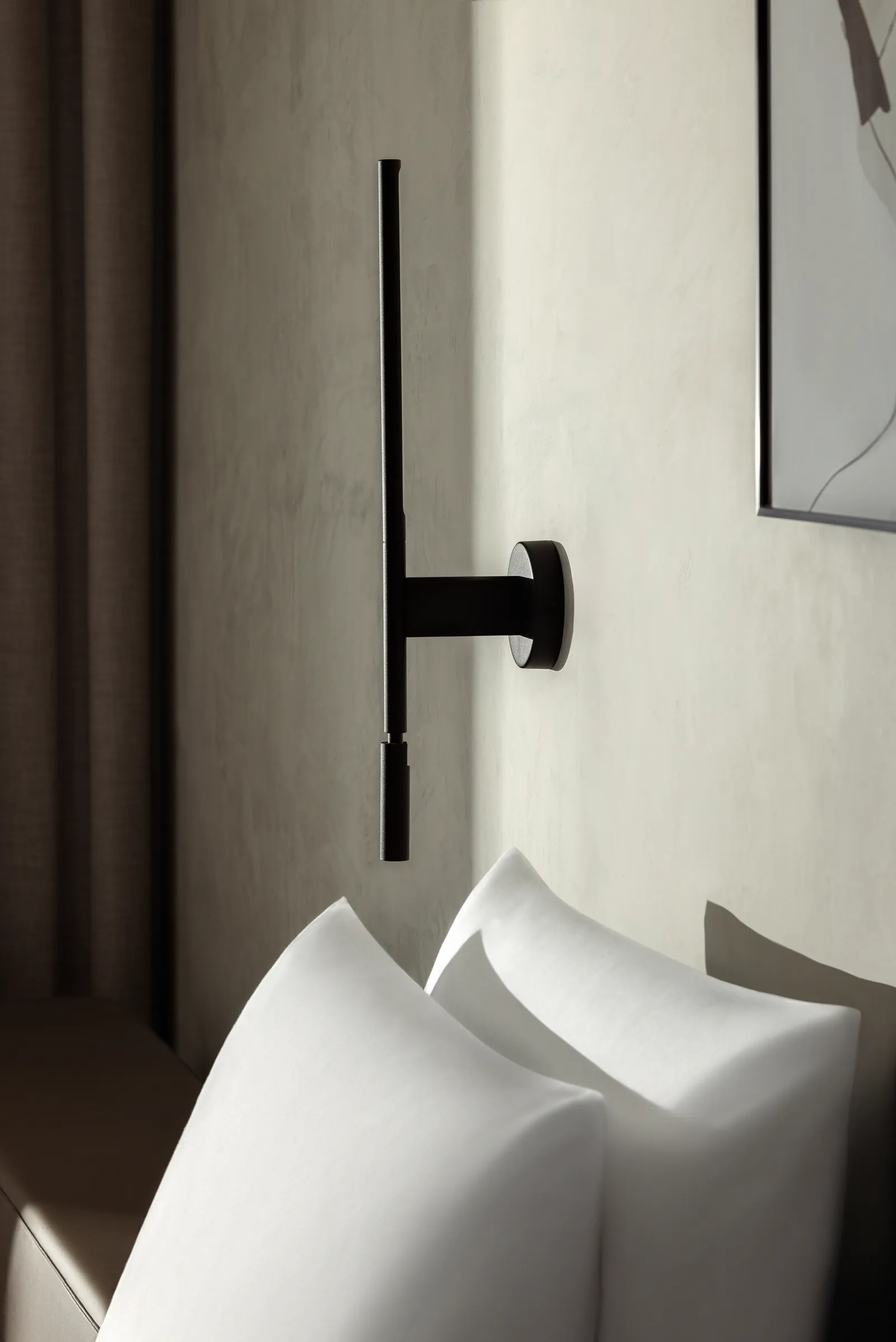 Black wall lamp above white pillows